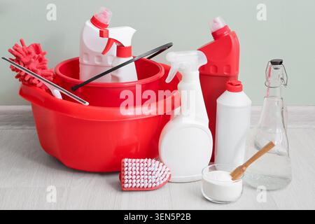 Household cleaning supplies and tools for home maintenance, red bucket with detergents, sprays, and brushes Stock Photo