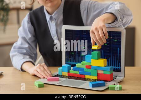 Business growth strategy and financial planning with wooden blocks on laptop keyboard displaying data charts, the laptop screen displays data charts a Stock Photo