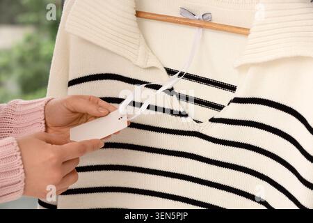 Woman's hands holding blank price tag on striped sweater, retail shopping and fashion industry Stock Photo