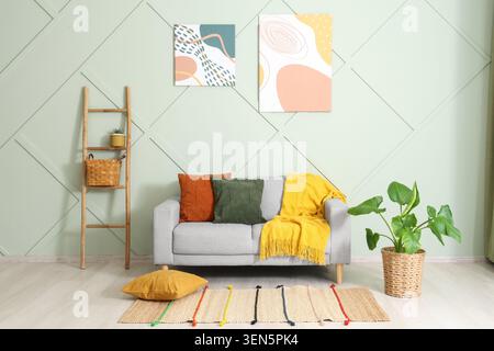 Modern living room interior design with gray sofa, colorful pillows, and abstract wall art decor Stock Photo