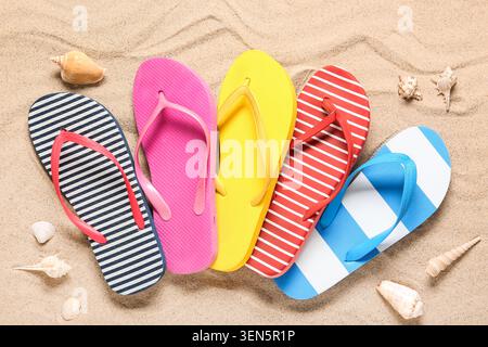 Colorful striped flip flops and seashells on sandy beach, summer vacation travel and leisure concept, the vibrant footwear and marine elements evoke a Stock Photo