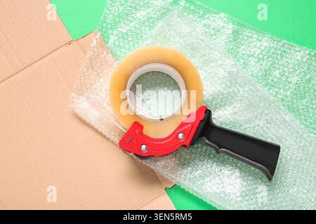 Packing tape dispenser with clear adhesive tape roll, bubble wrap, and cardboard box for shipping and moving Stock Photo