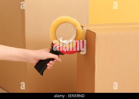 Hand taping cardboard box with packaging tape dispenser for moving, shipping, and storage logistics Stock Photo