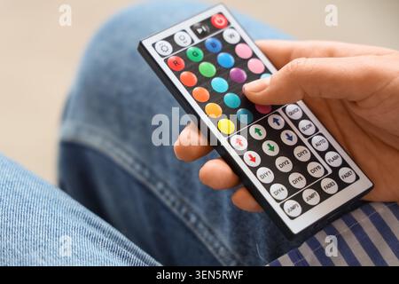 Hand holding modern LED light strip remote control with colorful buttons for smart home lighting and ambiance adjustment Stock Photo