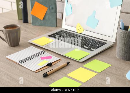 Laptop with colorful sticky notes and coffee mug on wooden desk, office workspace organization and productivity Stock Photo