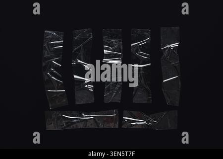 Clear adhesive tape strips with wrinkles and reflections on a dark black background abstract texture and material, the transparent material creates an Stock Photo