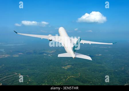 Commercial passenger jet airliner gains altitude after takeoff from a departure airport over green fields and forests high in the sky. Stock Photo