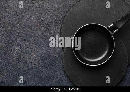 Small black frying pan on dark slate stone background, kitchen utensil for cooking and food preparation Stock Photo