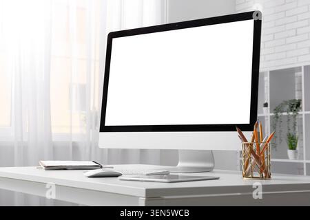Modern desktop computer with blank white screen on minimalist office desk, home workspace technology mockup Stock Photo