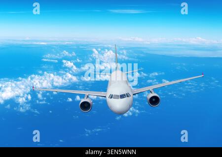 Airplane tilt turns flying in the sky front view. White clouds spreads across the horizon under vibrant blue sky Stock Photo
