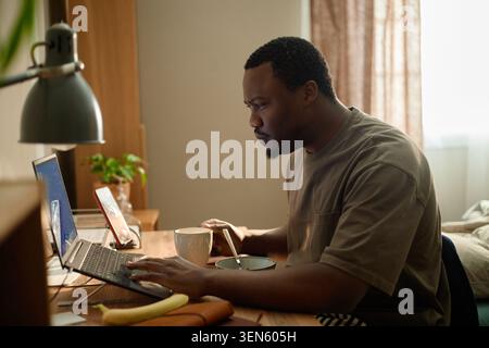 Black Man Using Laptop while Working from Home Stock Photo