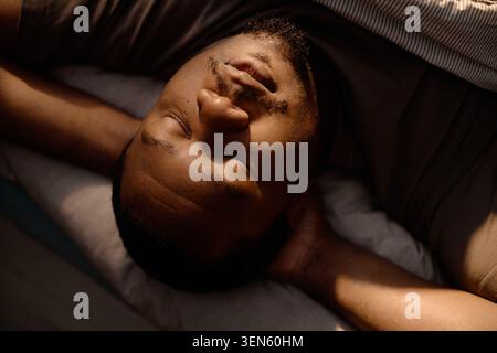Black Man Lying Awake in Bed Showing Fatigue at Home Stock Photo