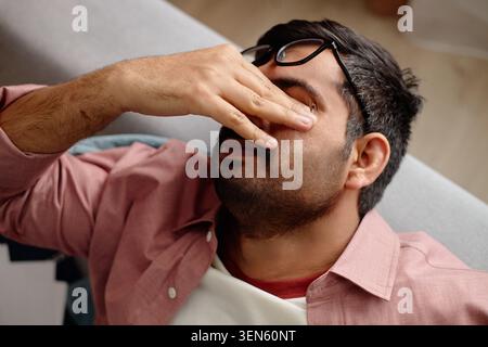Adult Man Rubbing Eyes While Feeling Tired at Home Stock Photo