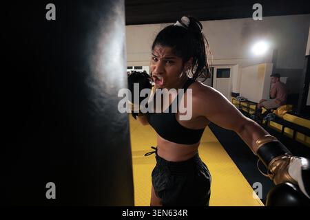 Female Boxer Training Intensely on Heavy Punching Bag in Gym During Sparring Session Stock Photo