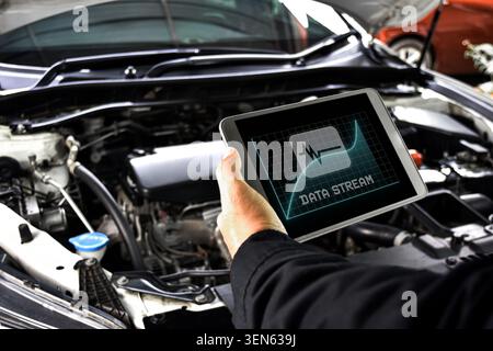 Mechanic diagnostics engine car using digital obd2 scanner tablet with data stream software at auto repair shop Stock Photo