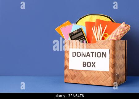 School supplies donation box with backpack, notebooks, pencils, and calculator for charity and education support Stock Photo