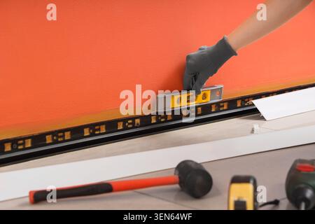 Home renovation and construction project with worker hand using level tool on wall baseboard installation Stock Photo
