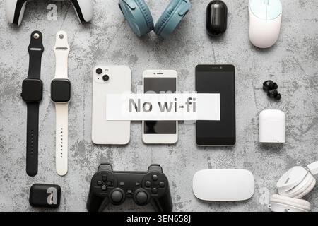 Digital detox with modern electronic devices and no wi-fi sign on concrete background, a white paper sign with "no wi-fi" text is placed over the smar Stock Photo