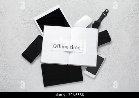 Digital detox with open notebook and "offline time" text surrounded by modern electronic devices Stock Photo