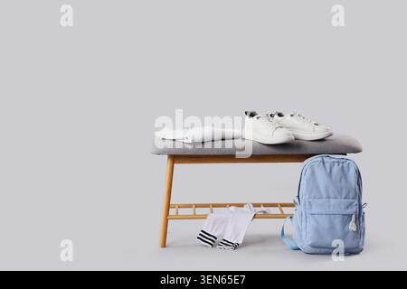 White sneakers, folded t-shirt, and blue backpack on wooden bench with socks, back to school essentials Stock Photo