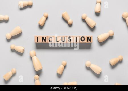 Inclusion word on wooden blocks with scattered peg dolls, diversity and equality concept, social justice and belonging Stock Photo