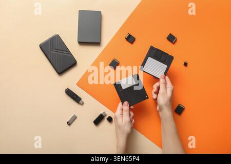 Data storage evolution: hands holding floppy disks with modern USB drives, memory cards, and external hard drives Stock Photo
