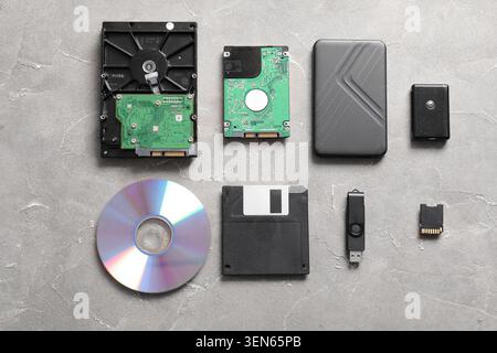 Evolution of data storage devices: hard drives, floppy disk, CD, USB flash drive, and memory card on gray background Stock Photo