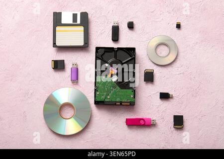 Digital data storage devices evolution flat lay with floppy disk hard drive cds USB drives and memory cards on pink background Stock Photo