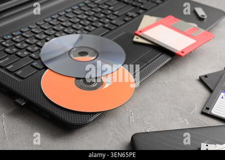 Obsolete data storage devices on laptop keyboard, retro technology evolution and digital archiving, the items are placed on a gray textured surface Stock Photo