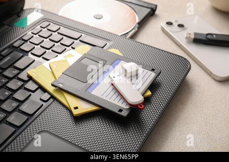 Digital data storage evolution: floppy disks, USB flash drive, laptop, and smartphone on desk Stock Photo