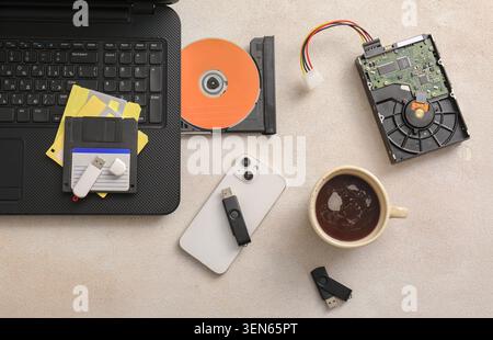 Digital data storage evolution: floppy disks, USB drives, hard drive, CD-ROM, and smartphone on laptop keyboard Stock Photo