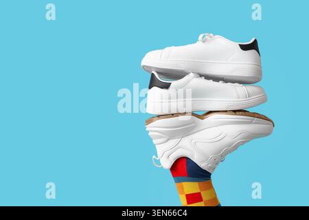 Stacked white sneakers on colorful striped sock against blue background, modern footwear fashion and lifestyle, this arrangement emphasizes product di Stock Photo