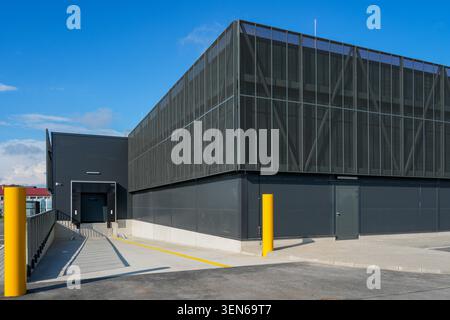 Contemporary warehouse loading dock and service access zone with protective bollards, metal facade and logistics infrastructure Stock Photo