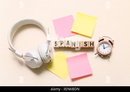 Spanish language learning with headphones, alarm clock, and sticky notes on a light background Stock Photo