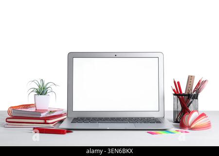 Modern laptop with blank screen on white desk, office supplies, and plant for remote work and online education Stock Photo