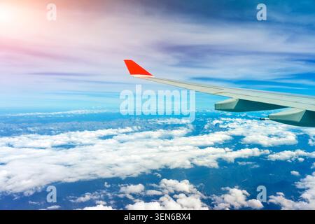 Wing view airplane cirrus, stratus and cumulus clouds surrounded by blue tropospheric haze over mountains. Stock Photo