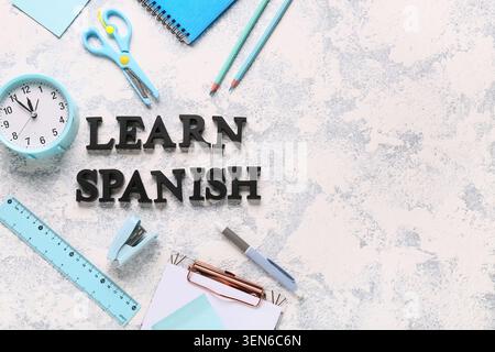 Learn spanish language education with desk clock, stationery, and text on textured background Stock Photo