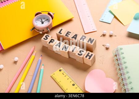 Learn spanish language education with wooden blocks, school supplies, and alarm clock on textured background Stock Photo