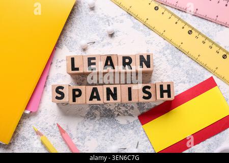 Learn spanish language education with wooden blocks, notebooks, rulers, and pencils on textured background Stock Photo