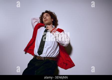 A handsome young man in stylish attire relaxes, revealing a mix of emotions and confidence. Stock Photo