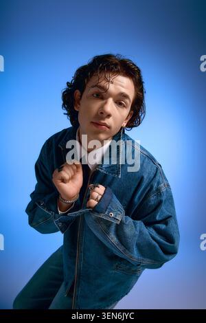 Handsome young man showcases fashionable denim jacket while displaying a range of emotions. Stock Photo
