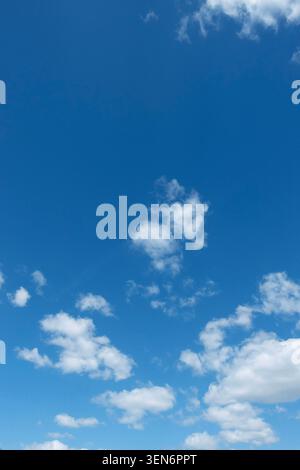 Blue summer sky with scattered white clouds, a peaceful weather background with copy space and natural daylight Stock Photo