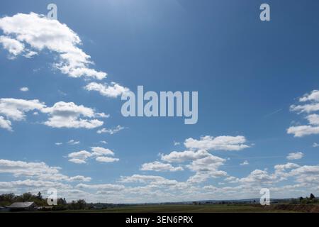 Blue summer sky with scattered white clouds, a peaceful weather background with copy space and natural daylight Stock Photo
