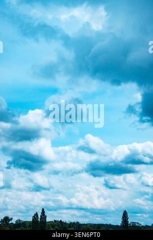 Dramatic cloudy sky over a green landscape, with dark storm clouds and soft blue light after rain Stock Photo