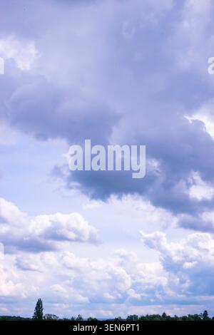 Dramatic cloudy sky over a green landscape, with dark storm clouds and soft blue light after rain Stock Photo