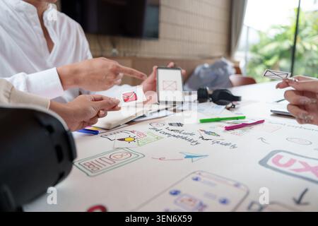 Business team hands collaborating on UI UX design creative process with mobile phone in office meeting Stock Photo