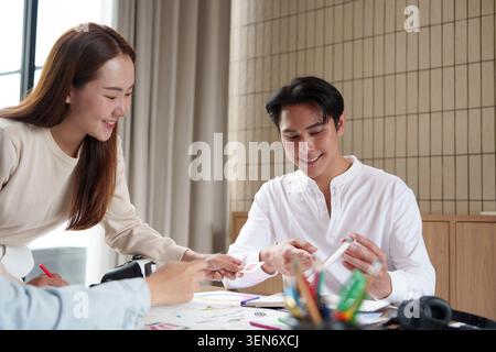 Asian business team collaborating on UI UX design creative process in modern office meeting teamwork Stock Photo