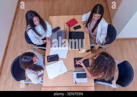 Businesswomen collaborating around a table, planning strategy during an office meeting, brainstorming ideas, and discussing work Stock Photo