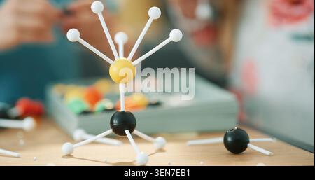 Project, science and person with atom model on desk for studying, education or assignment in house. Learning, homework and toy structure of molecule Stock Photo
