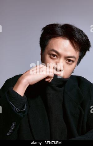 Fashion forward young asian  man poses confidently in a stylish outfit Stock Photo